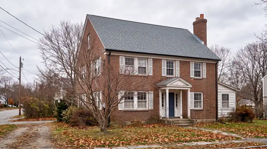 The same house after: a new slate-grey architectural shingle roof and new black gutters.